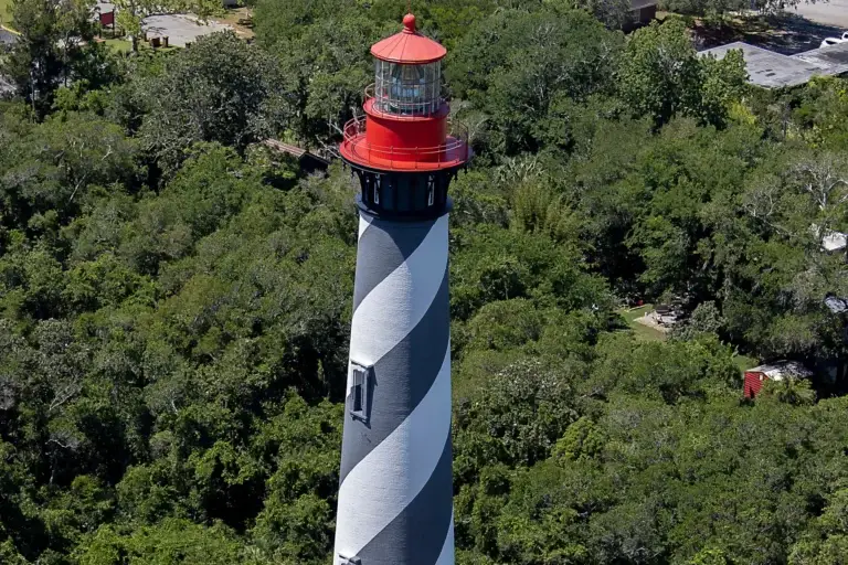 Farol de St. Augustine com listras pretas e brancas espirais visto entre a vegetação